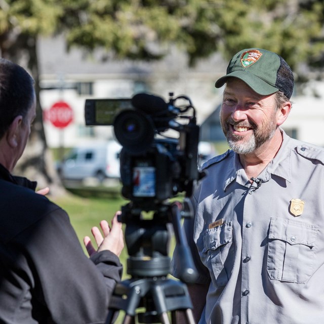 A park employee stands in front of a camera and answers questions.