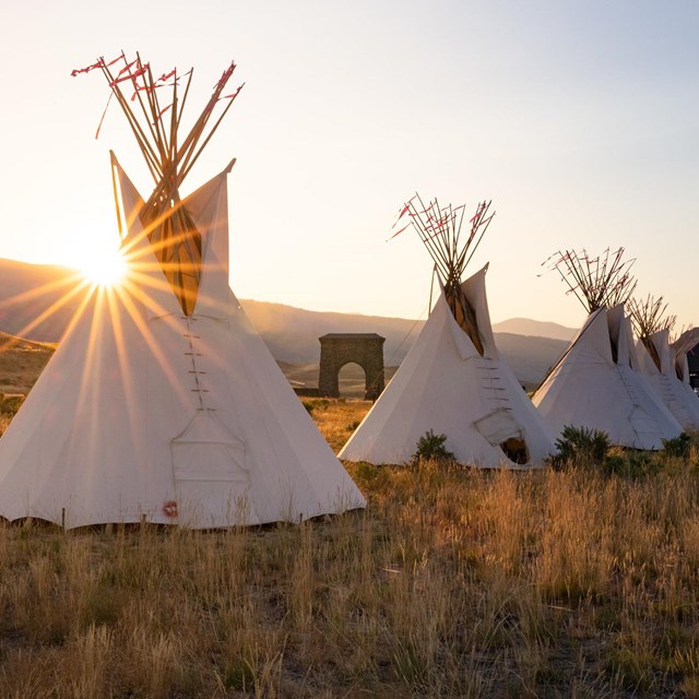 Teepees at the North Entrance in Gardiner with the Roosevelt Arch and setting sun