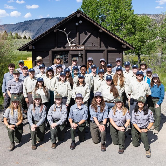 A large group of people in matching uniforms smiling on a summer day