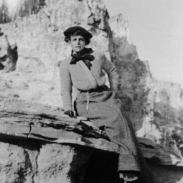 Frances Benjamin Johnston, full-length portrait, seated on rock in Yellowstone National Park, facing
