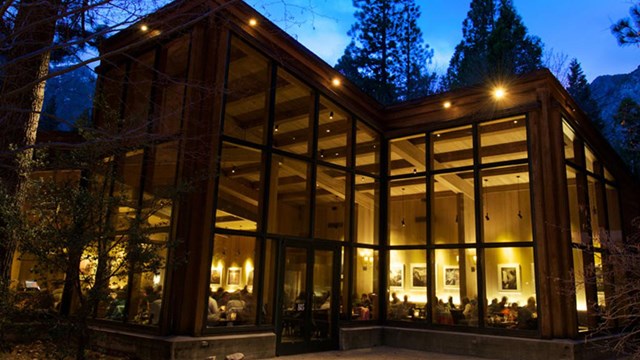 Tall, lighted windows of the Mountain Room restaurant at night.