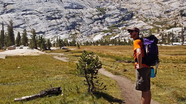 A hiker stands on a trail near Cathedral Lakes