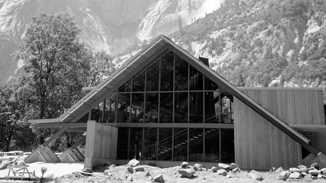 A new A-frame building with almost a full wall of windows and wood paneling; a concrete sign with le