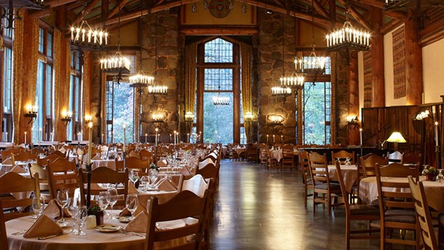 Tall dining room with open beams, high windows, and chandeliers.