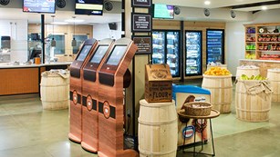 Interior of a small food court, with sandwich counter and bins of packaged snacks.