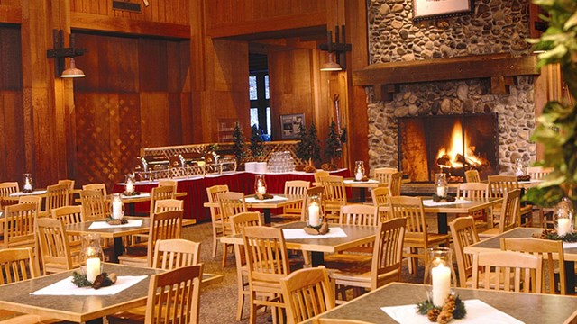 Large cozy indoor space with stone fireplace and wooden chairs.