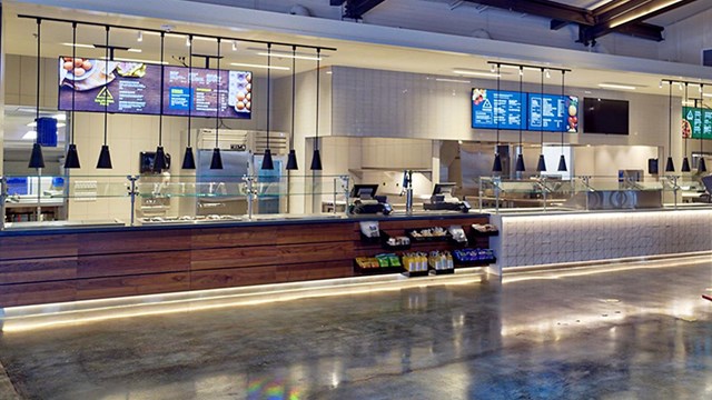 Empty food court counters with menus posted behind them.