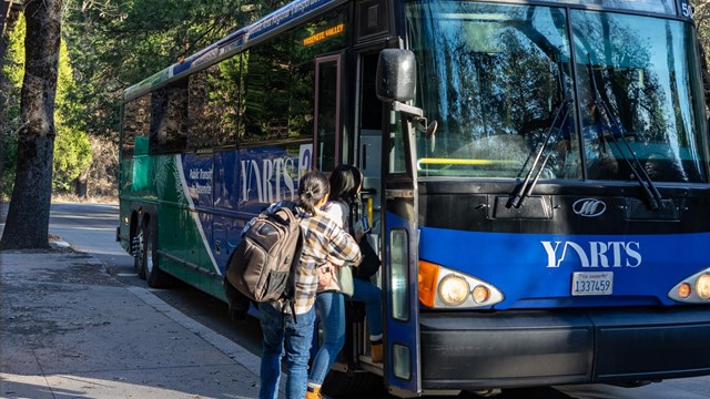 Two passengers board a blue YARTS bus.