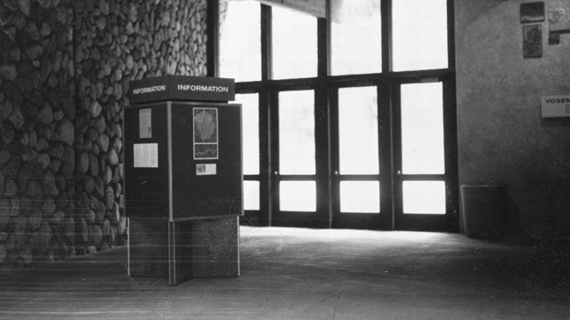 The interior of a building with an information kiosk and a rock wall