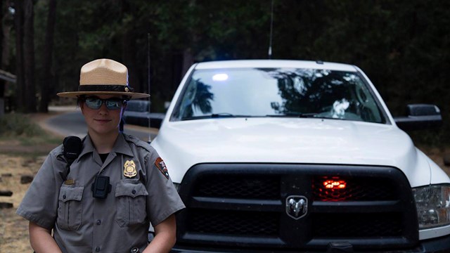 Law enforcement ranger standing in front of her vehicle.