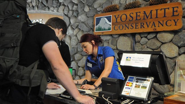 Yosemite Conservancy bookstore employee at the sales desk in Yosemite Valley at the visitor center.