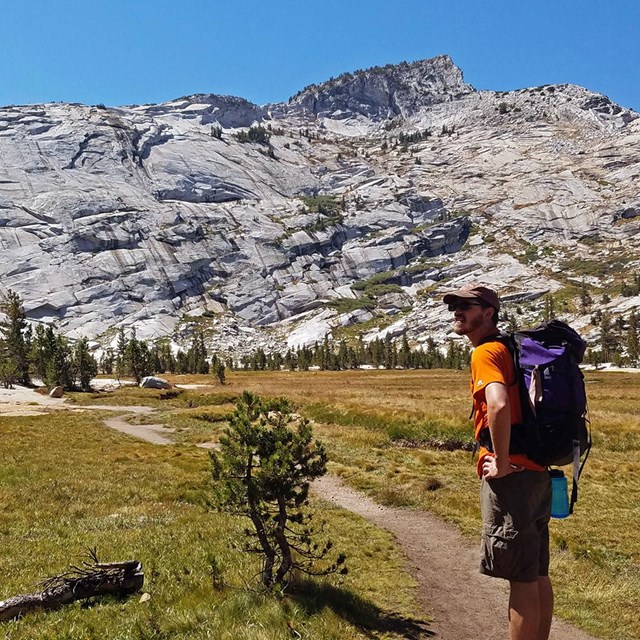 A hiker stands on a trail near Cathedral Lakes