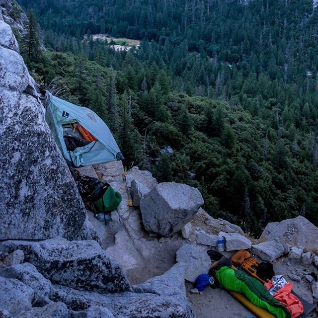 Climbers sleeping on a ledge on a rock wall in Yosemite Valley.
