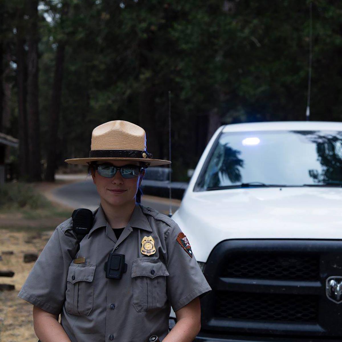 Law enforcement ranger standing in front of her vehicle.