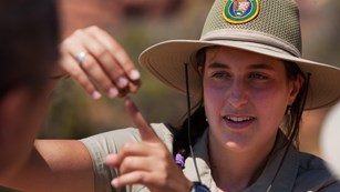 a woman in brown uniform gestures with her hands