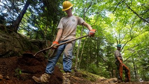 Youth Conservation Corp member working in the field with a shovel.