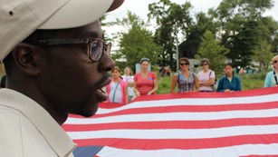 Young man talking with a giant U.S. flag in the background