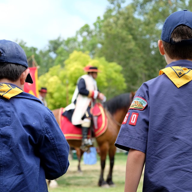 Cub Scouts looking at a living historian portraying a Spanish explorer on horseback