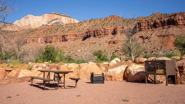 A picnic table and elevated fire pit on a flat surface.