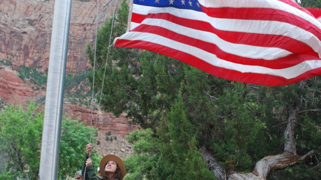 Ranger raises flag in front of Visitor Center.