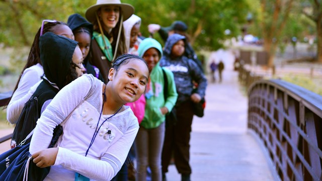 students walking on a bridge over a stream