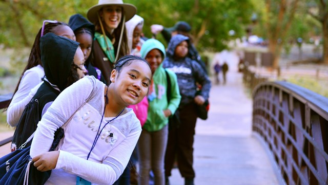 students walking on a bridge over a stream