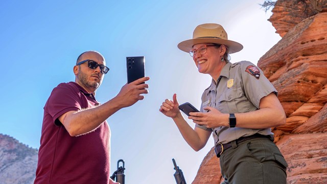 A Ranger checks a permit while surrounded by red rocks.