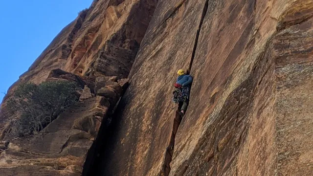 A person climbs a tall cliff in Zion National Park.