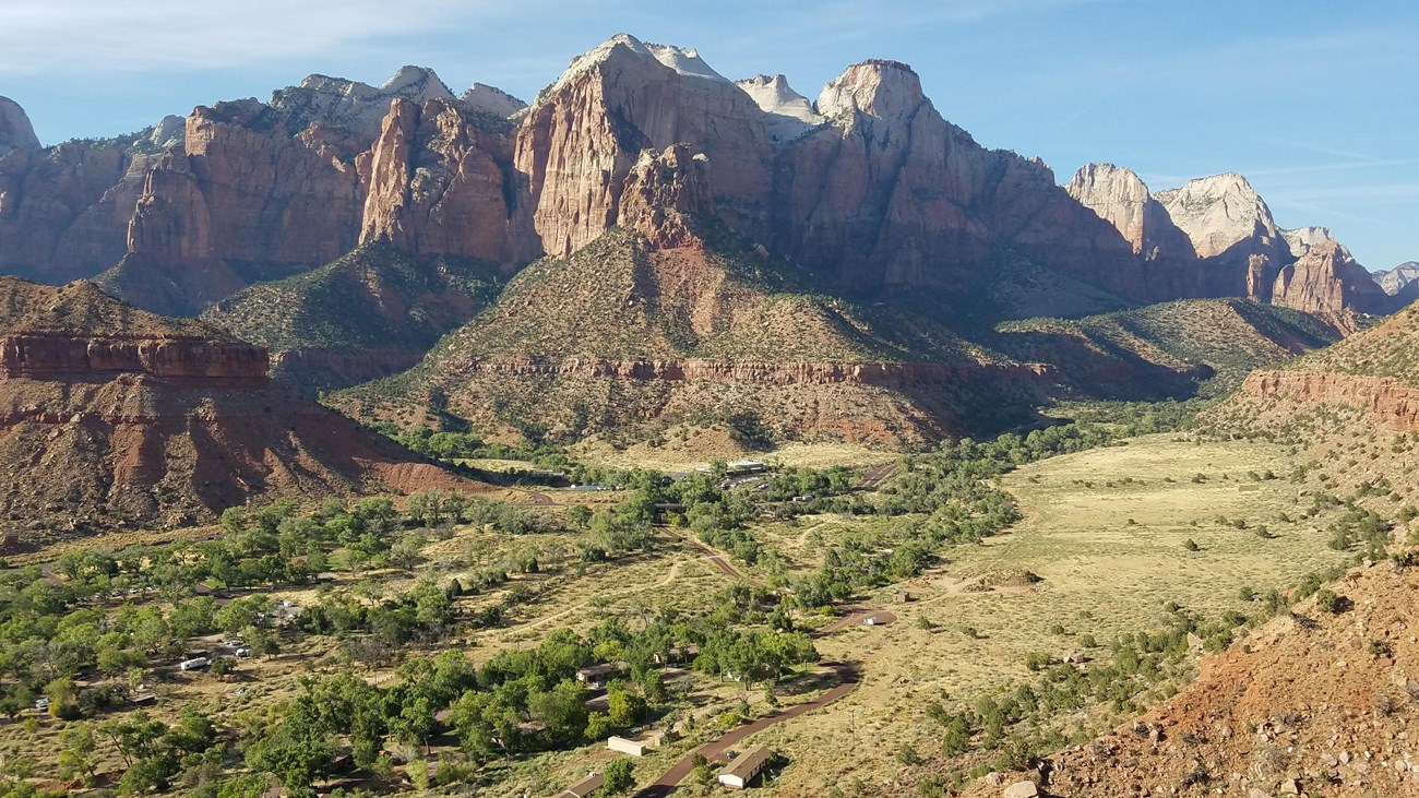 A large canyon under towering sandstone cliffs.