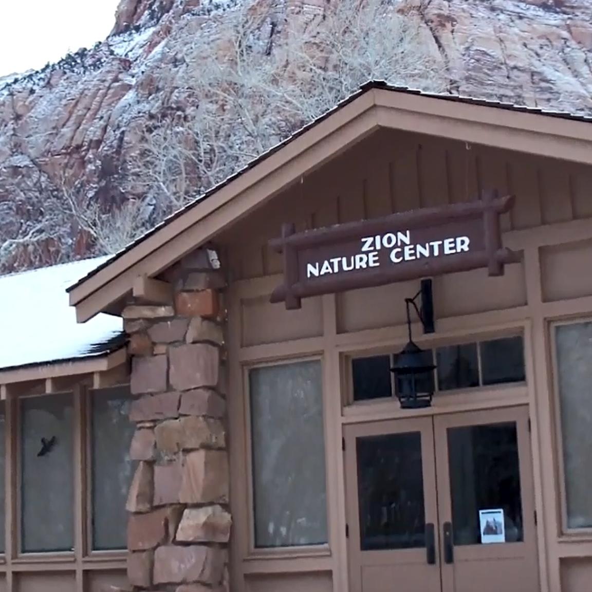 A stone building covered in snow with towering cliffs in the background.