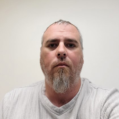 Headshot of man in white shirt with beard