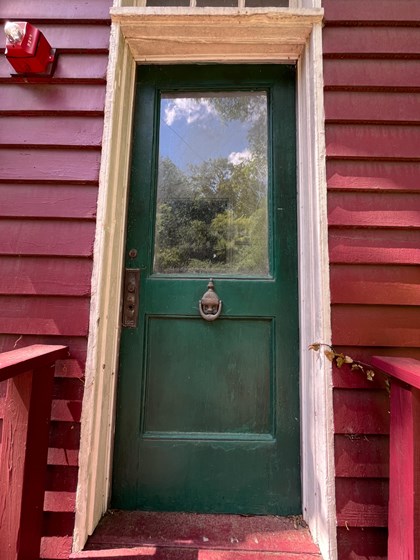 a dark green door with a large window and an ornamental knocker below the window