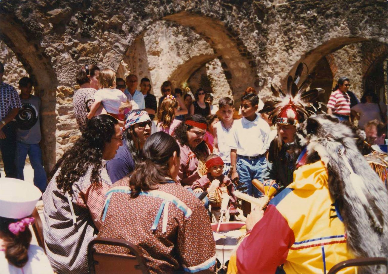 Group of native Americans sitting around at a historic site