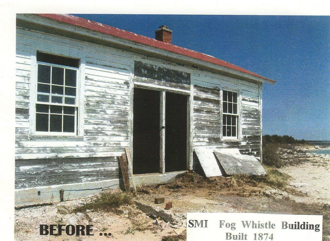A run-down, rectangular building with peeling white paint and a red roof.