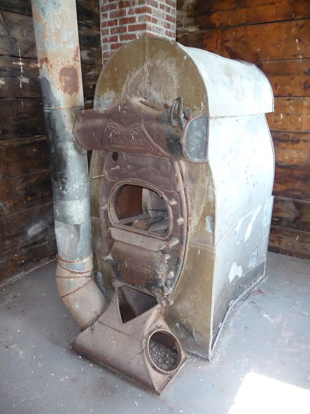 A brown arched furnace with a cylindrical duct next to it.