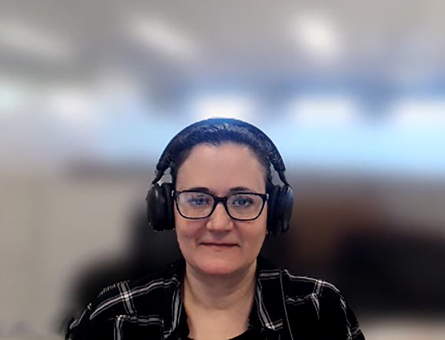 Woman in black garment with headphones in front of a blurred background