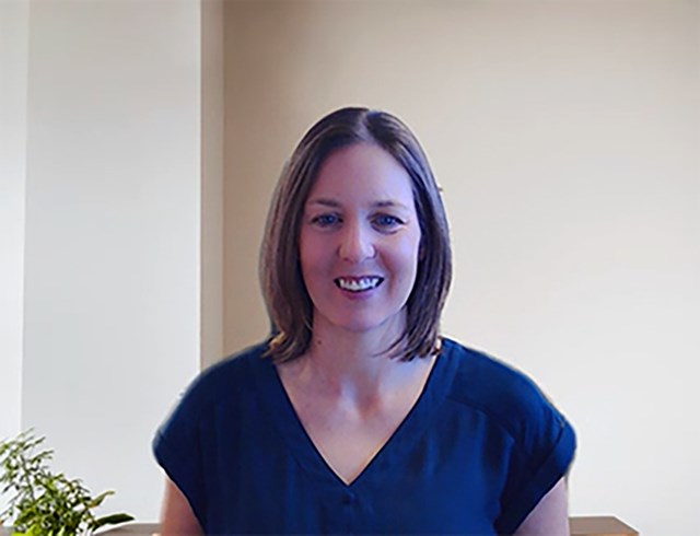 Smiling woman with brown hair in a dark blue garment