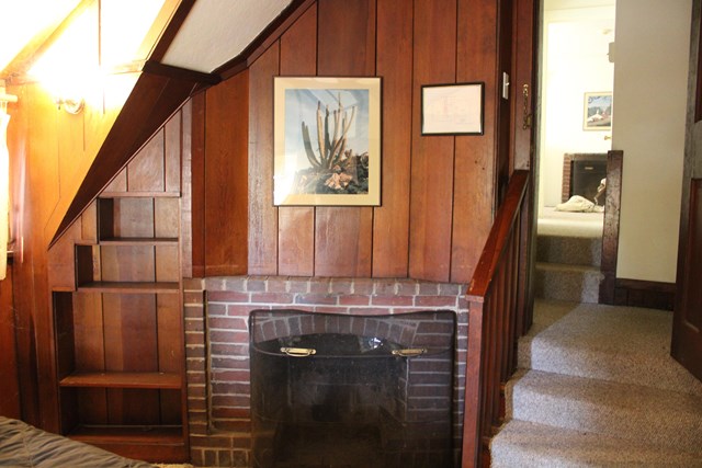 wood paneled wall, brick fireplace, and shelves built into the wall
