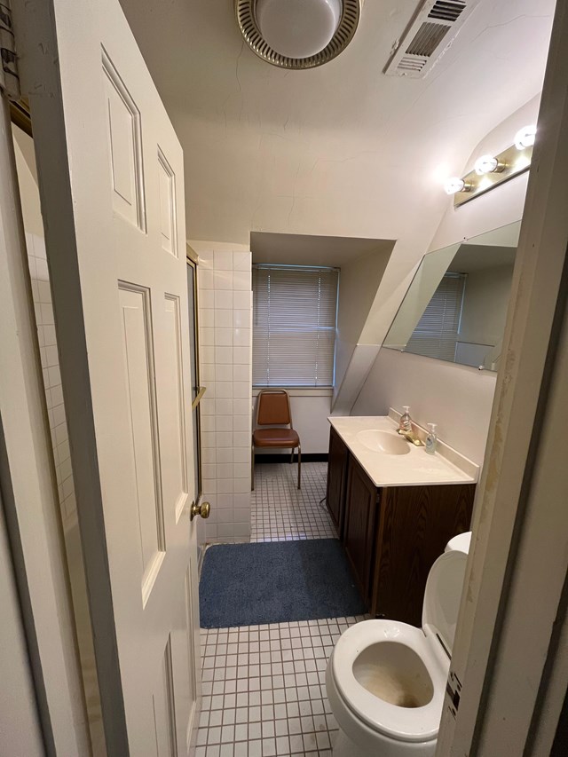 view from the hallway looking into a small bathroom, showing the window, sink, mirror, and toilet