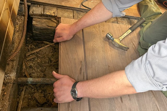 NPS employee repairing the subfloor of a historic building. 