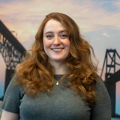 Headshot Photo of Kierstin Klimas with a bridge and clouded sky background.