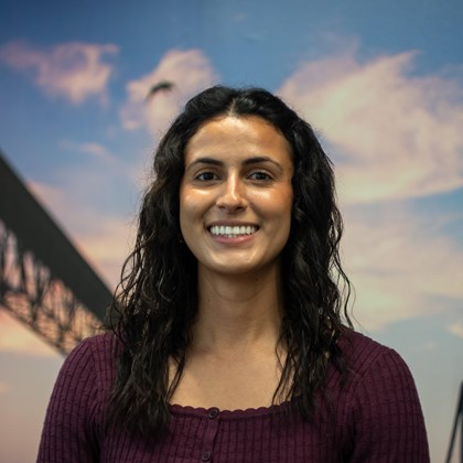 Headshot Photo of Aurelia Gracia with a bridge and clouded sky background.