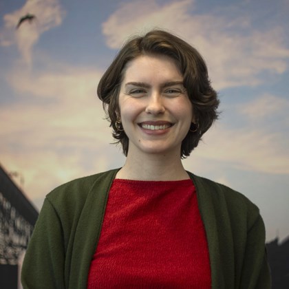 Headshot Photo of Eleanor Gross with a bridge and clouded sky background.