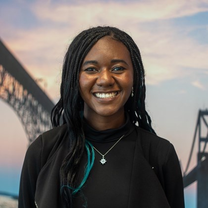 Headshot Photo of London Cobb with a bridge and clouded sky background.