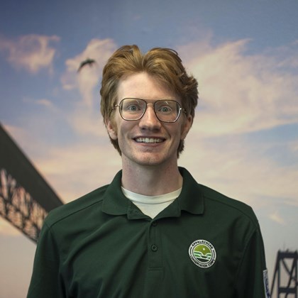 Headshot Photo of Eric Lindsay with a bridge and clouded sky background.