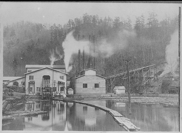 A black and white photo of some buildings near a pond.