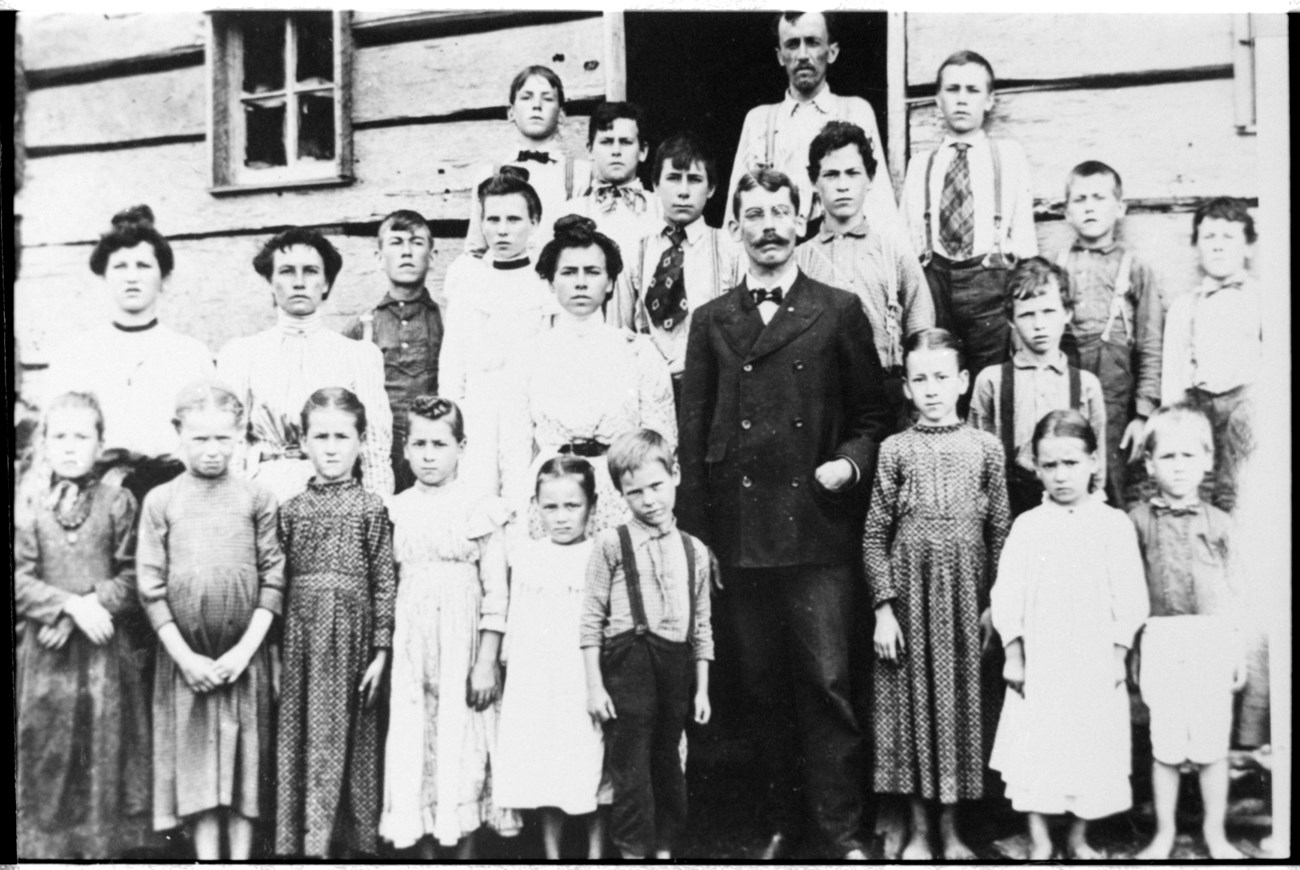 A large group of people pose for a photo in front of a building. 