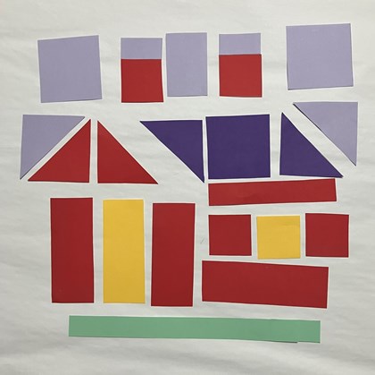 Paper laid out to eventually form parts of a quilt block in the shape of a house. 
