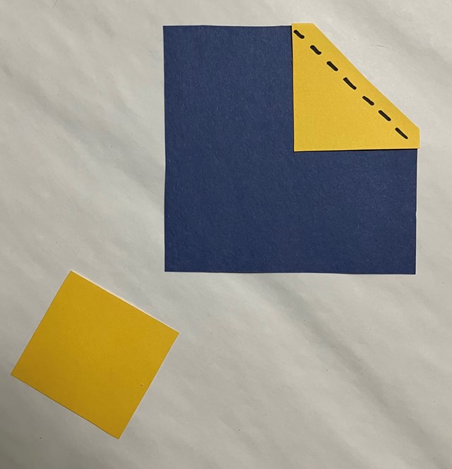  One large blue square and 2 yellow squares, one yellow on the blue square with dotted line folded.