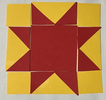 An 8-pointed red star on a yellow background made out of paper.